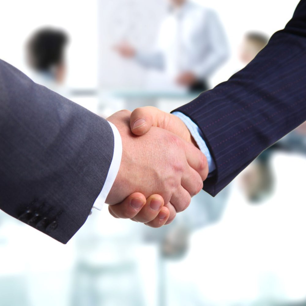 Business handshake. Two businessman shaking hands with each other in the office